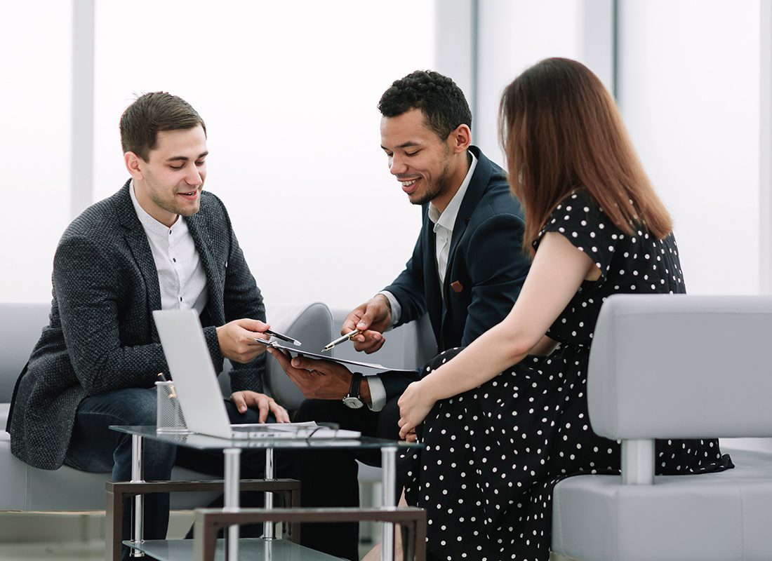 Contact - An Agent is Reviewing Documents to Sign With Two Clients at an Office