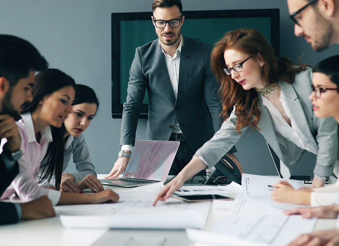 Insurance Solutions - Group of Professionals are all Reviewing Documents at a Meeting in an Office